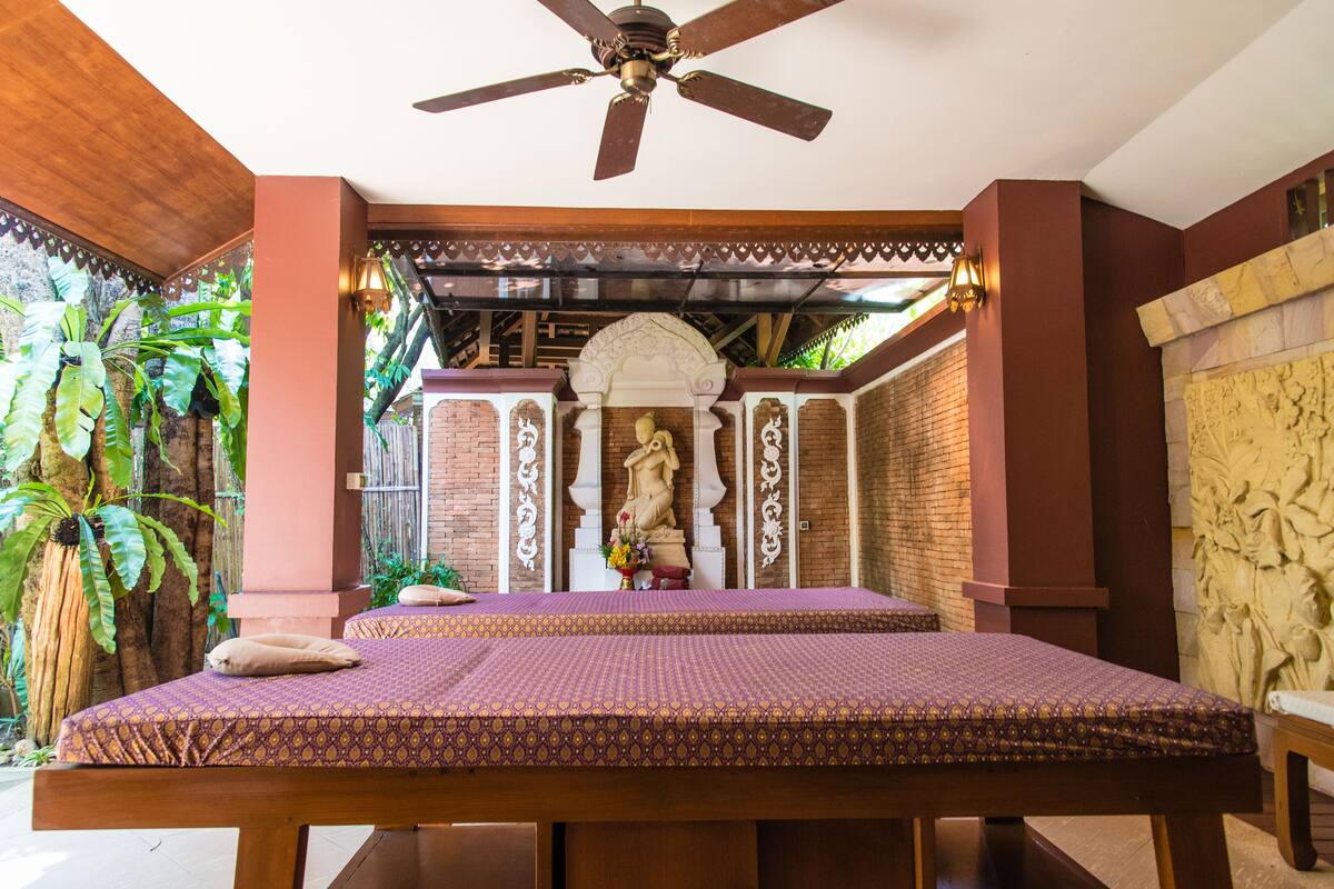 A room with a bed, ceiling fan, and a statue.