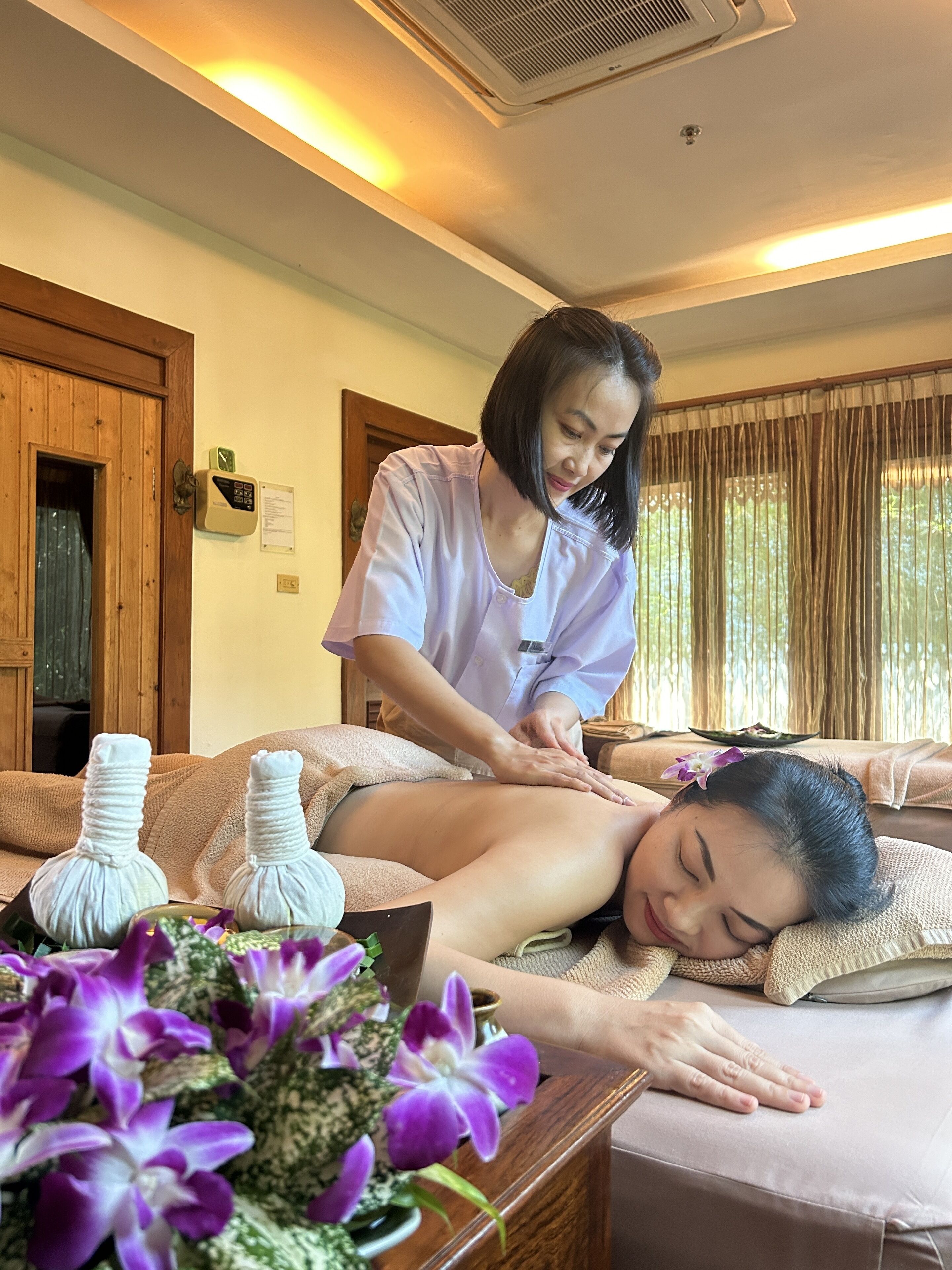 A massage therapy session in a room with wooden doors, a massage table, and a flower arrangement.