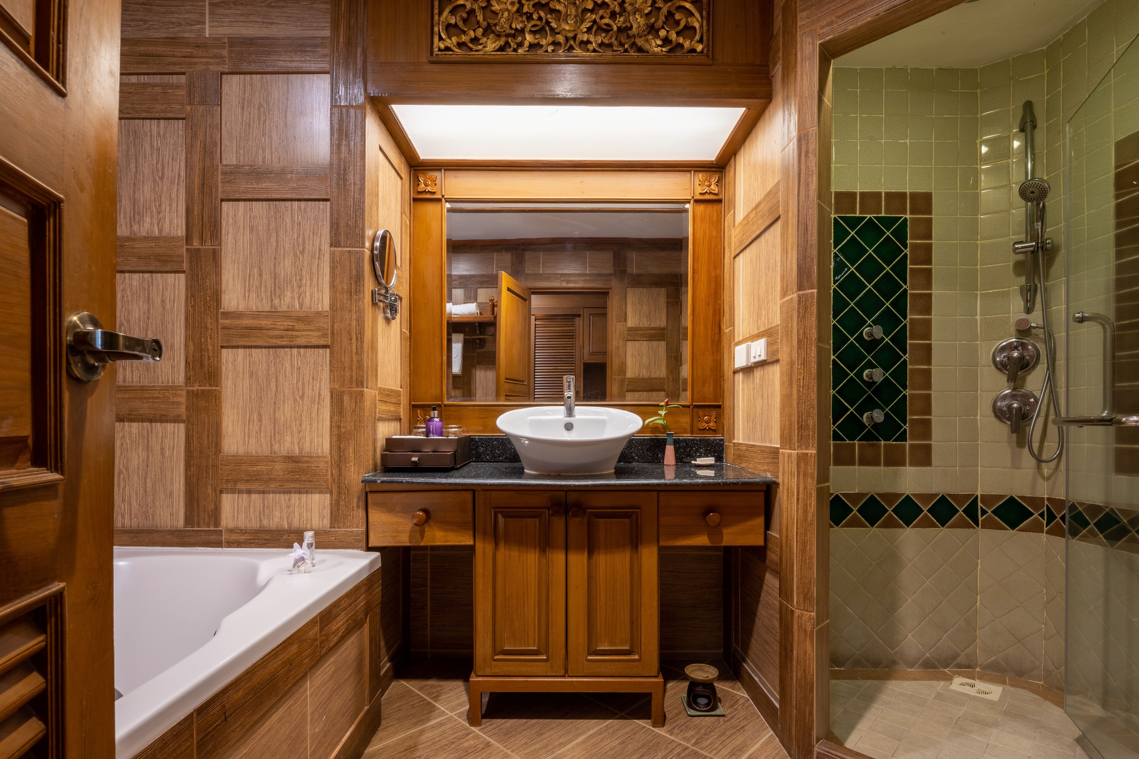 A bathroom with a wooden vanity, a freestanding bathtub, and a glass-enclosed shower area.