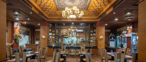 A restaurant with a central altar, wooden ceiling, and chandeliers. Tables are set with chairs, and there are decorative elements on the walls.