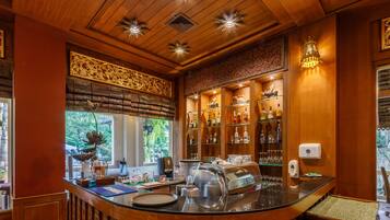 Eine Bar mit einer Theke, Barhocker, einer Kaffeemaschine und Regalen mit Flaschen und Gläsern.