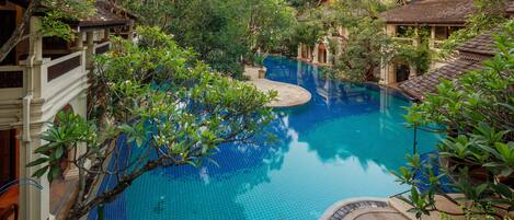 A pool surrounded by lush greenery and traditional architecture.