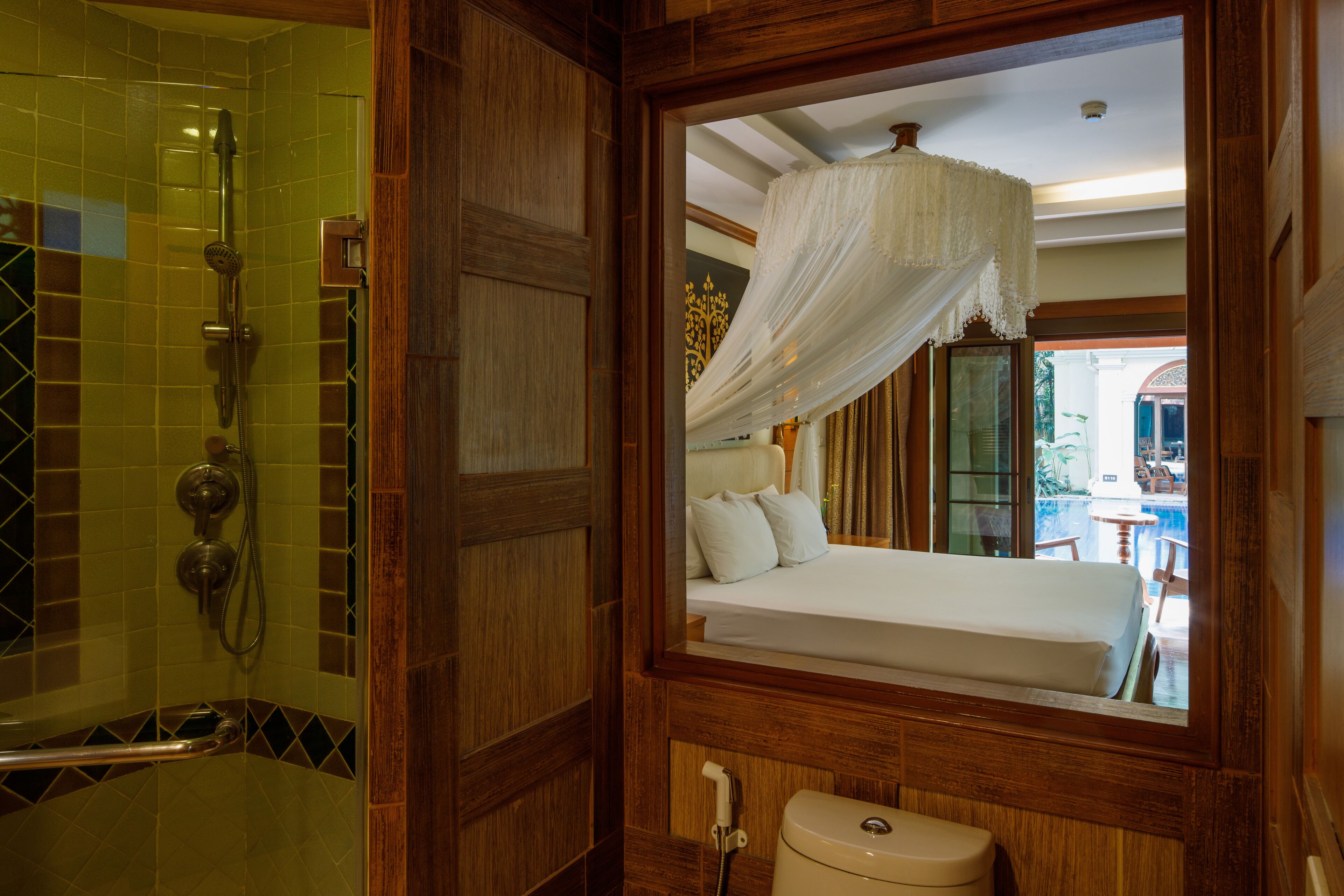 A bathroom with a shower, toilet, and a bed with a canopy.