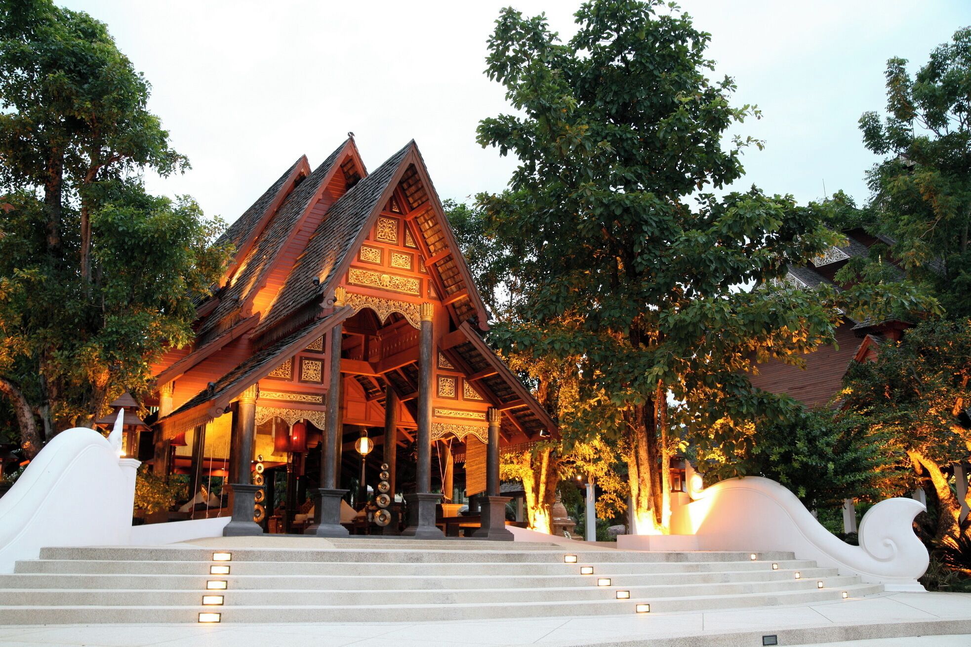 A traditional wooden structure with a steeply pitched roof, surrounded by trees and steps leading up to it.
