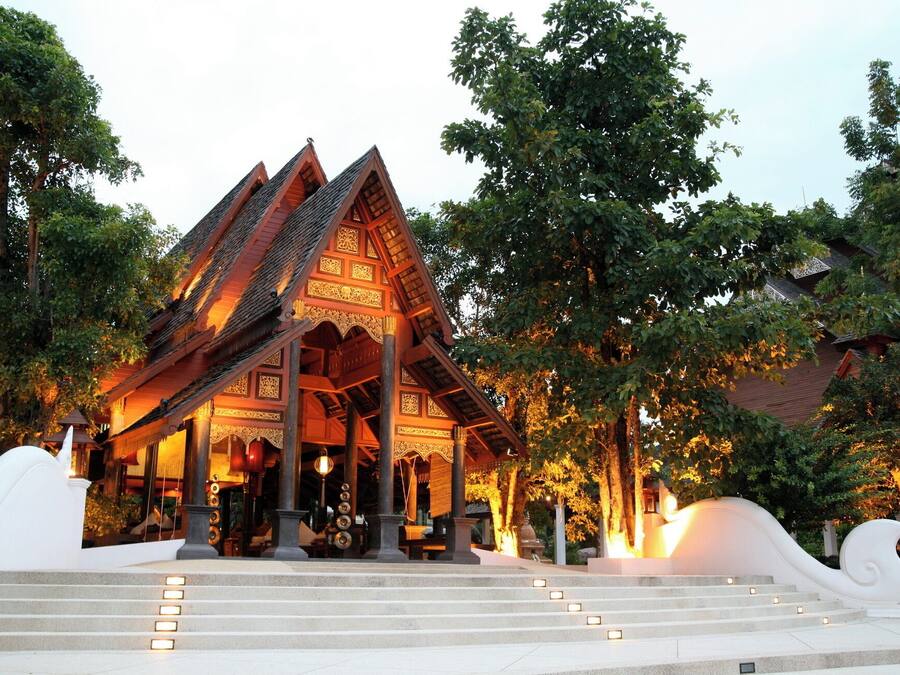 A traditional wooden structure with a steeply pitched roof, surrounded by trees and steps leading up to it.