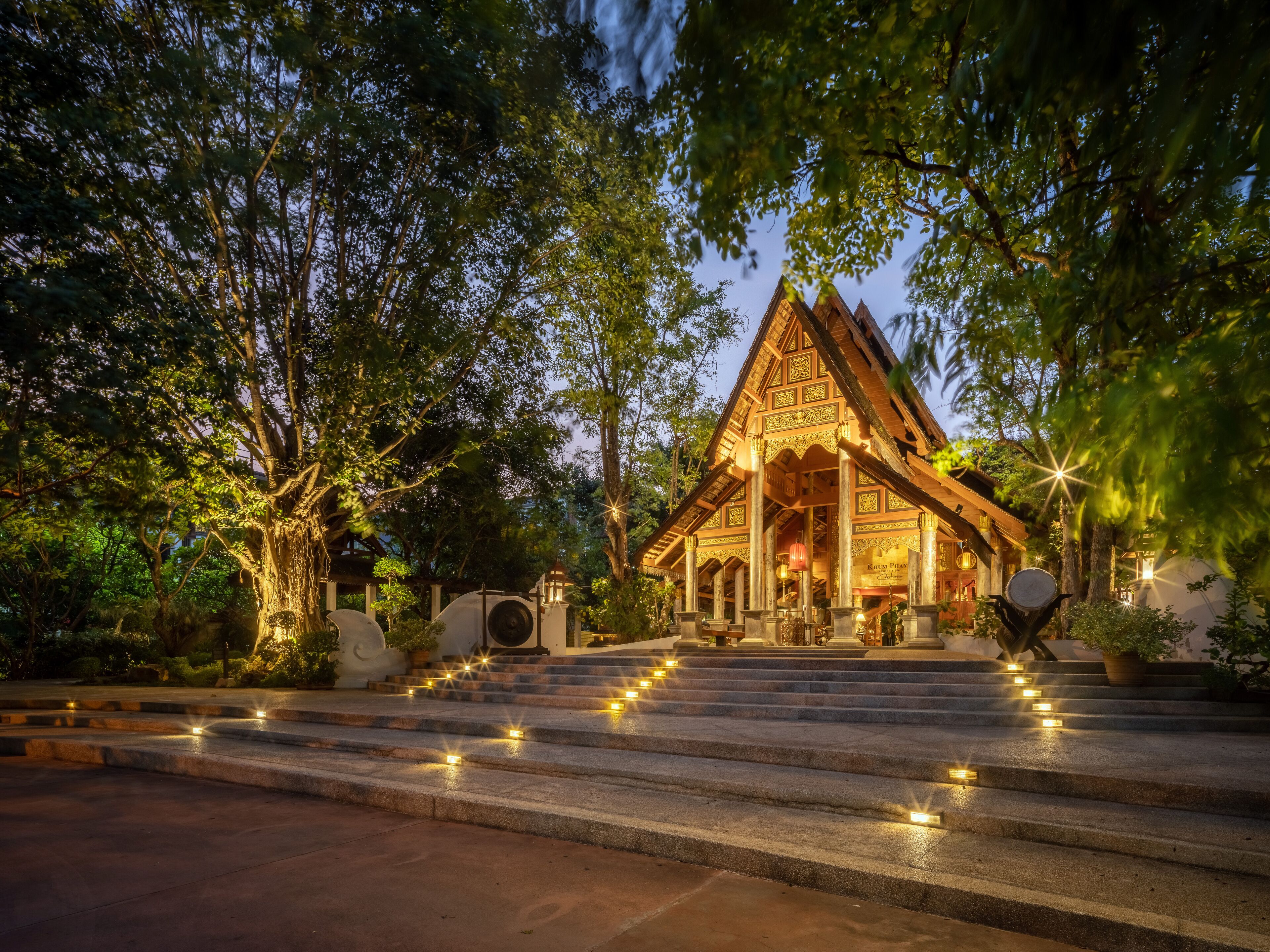 Una estructura de madera tradicional con techo inclinado, rodeada de árboles e iluminada con pequeñas luces.