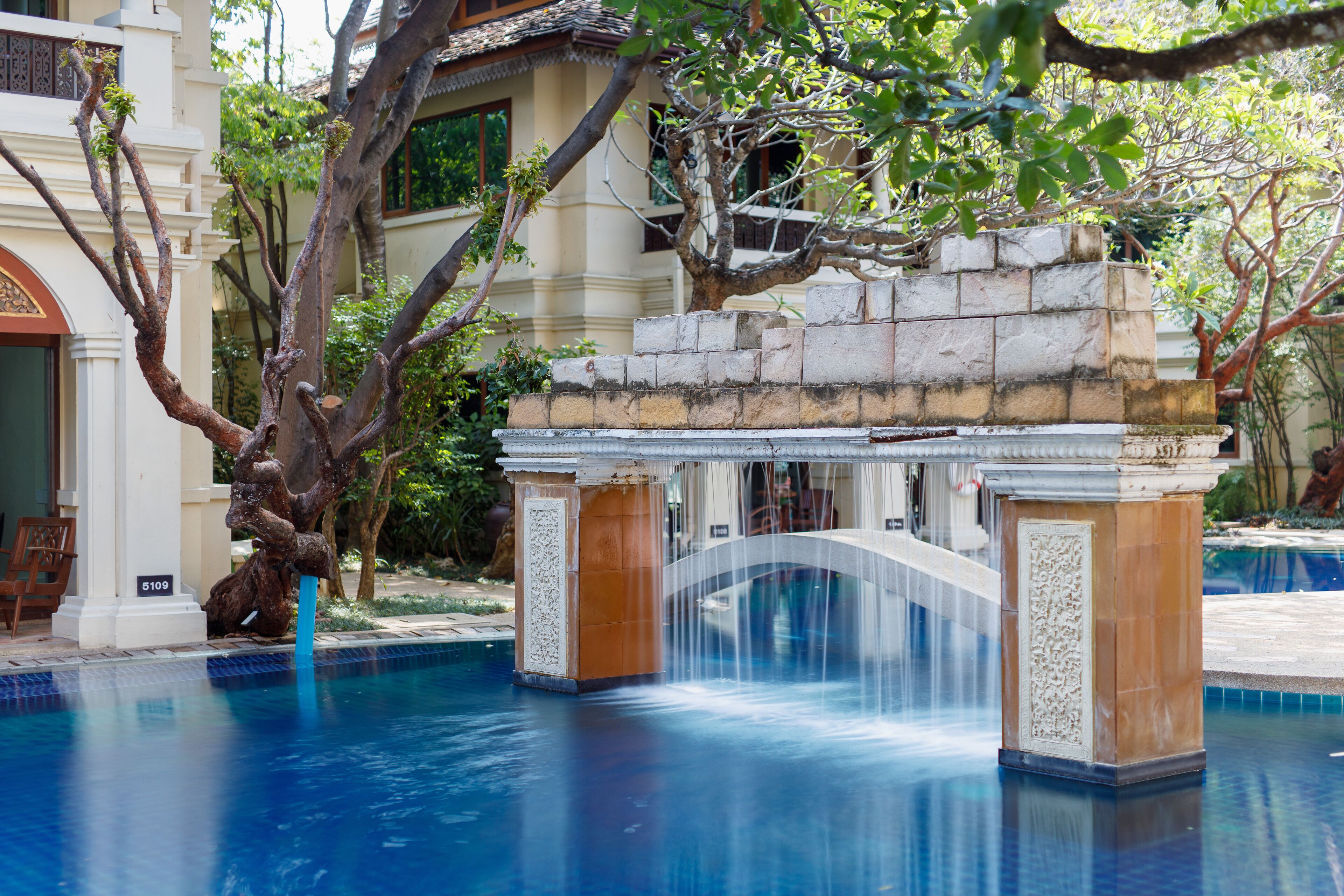 A pool with a stone bridge and a waterfall.