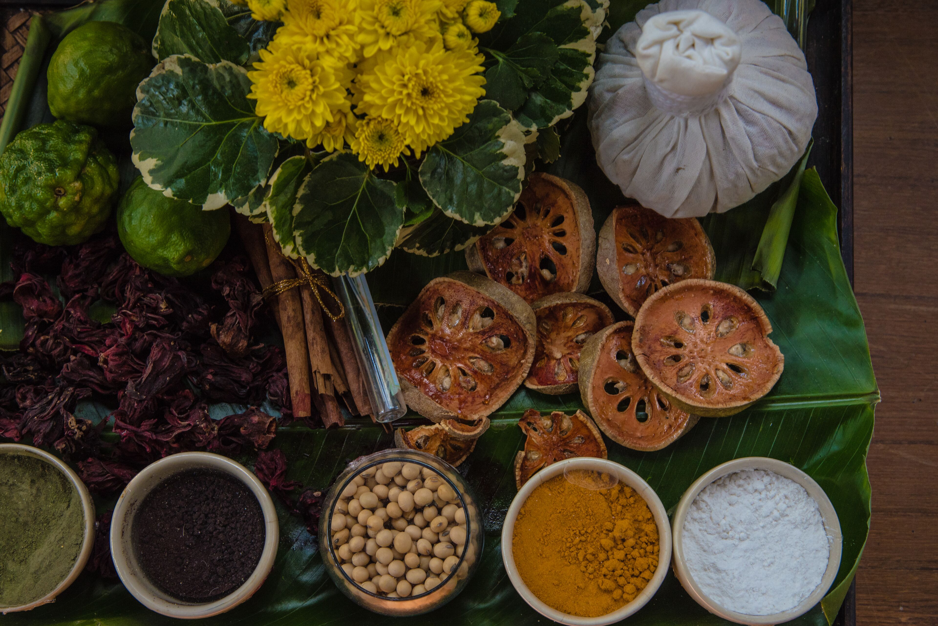 Una bandeja con diversas especias, flores secas y un objeto blanco sobre una hoja verde.