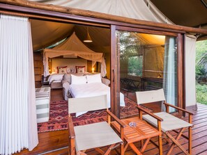 Alojamiento con tienda, cama, dosel y mesa con sillas.