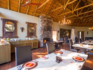 Comedor con chimenea de piedra, techo de madera y mesas de buffet.