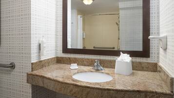 A bathroom with a sink, mirror, and towel dispenser.