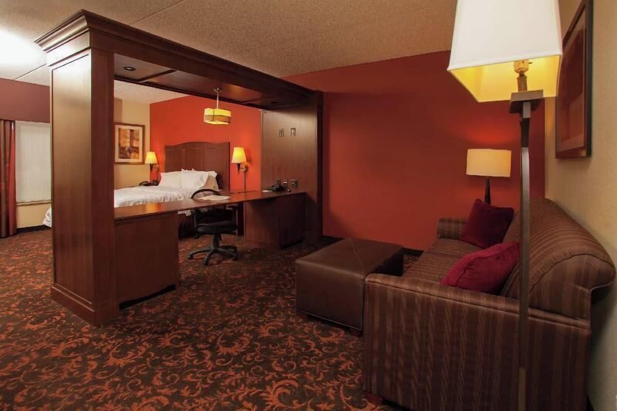 A hotel room with a bed, desk, chair, and a sofa.