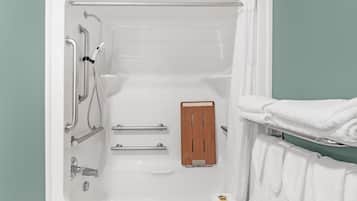 Une baignoire avec un panneau en bois, des barres d’appui et un porte-serviettes.