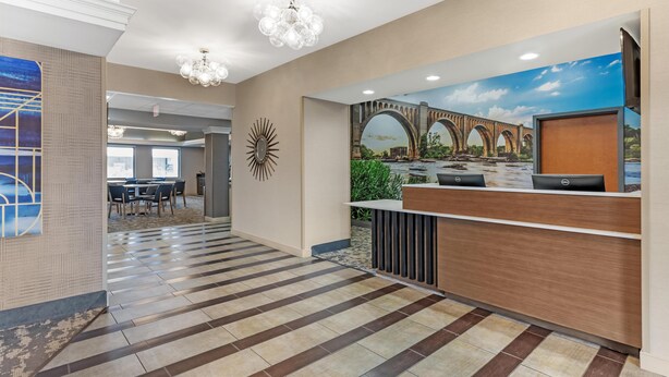 A hotel reception area with a reception desk, a large mural of a bridge, and a chandelier. - Best Western Plus Glen Allen Inn (Glen Allen)