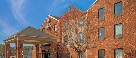 Un bâtiment en briques avec une entrée couverte, une enseigne « Best Western Plus » et un arbre devant.