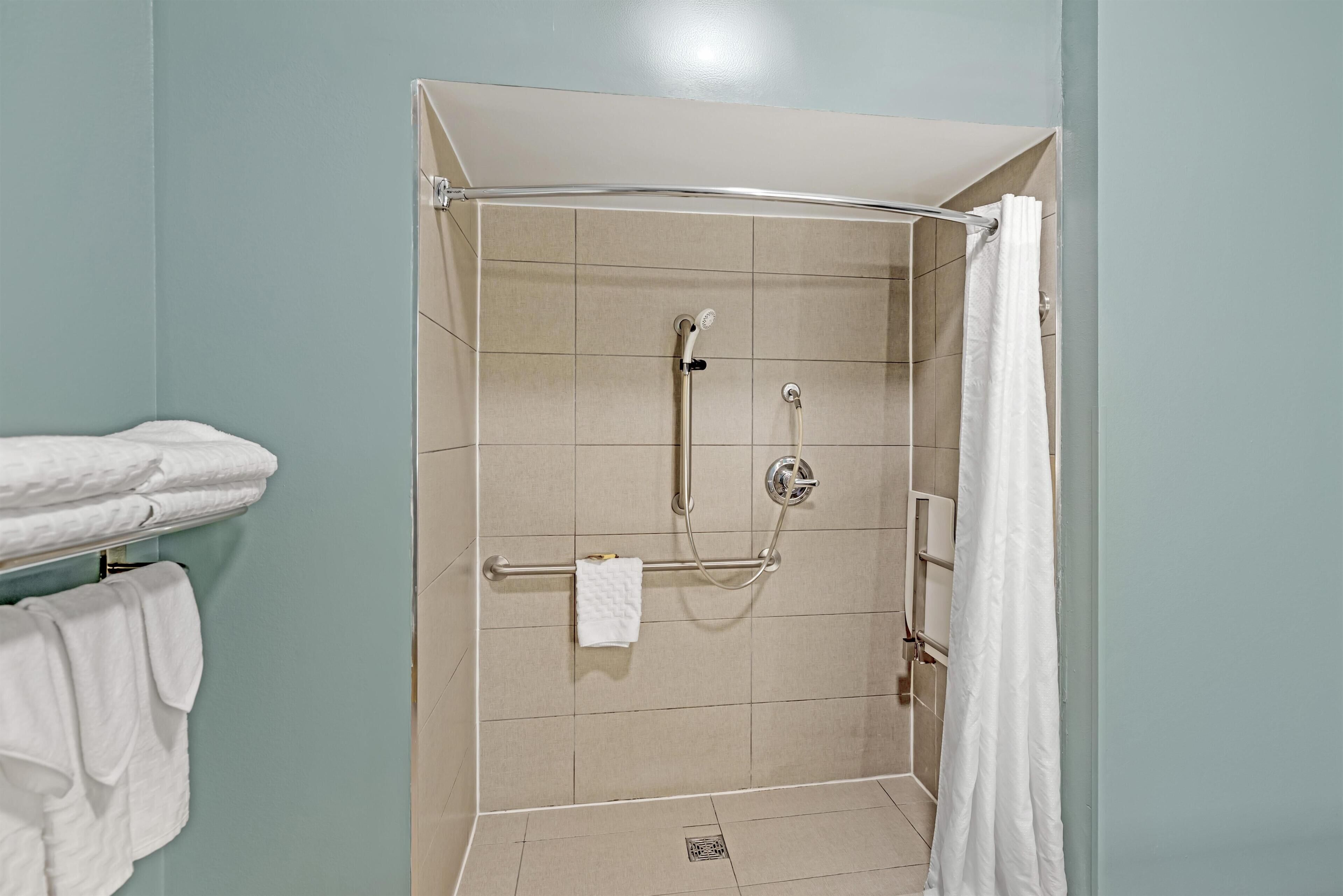 A shower with a glass door, a towel rack with towels, and a shower control panel.