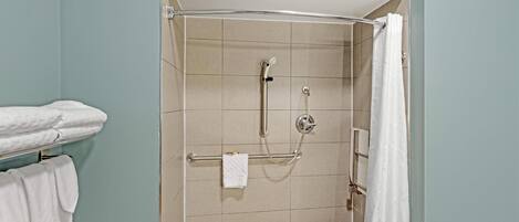 Una ducha con puerta de vidrio, un perchero con toallas y un panel de control de la ducha.