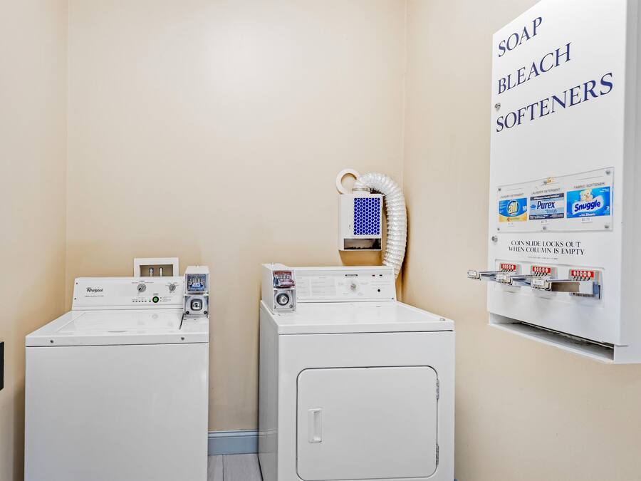A laundry area with two washers and dryers, a soap and bleach softener dispenser, and a coin-operated dryer.