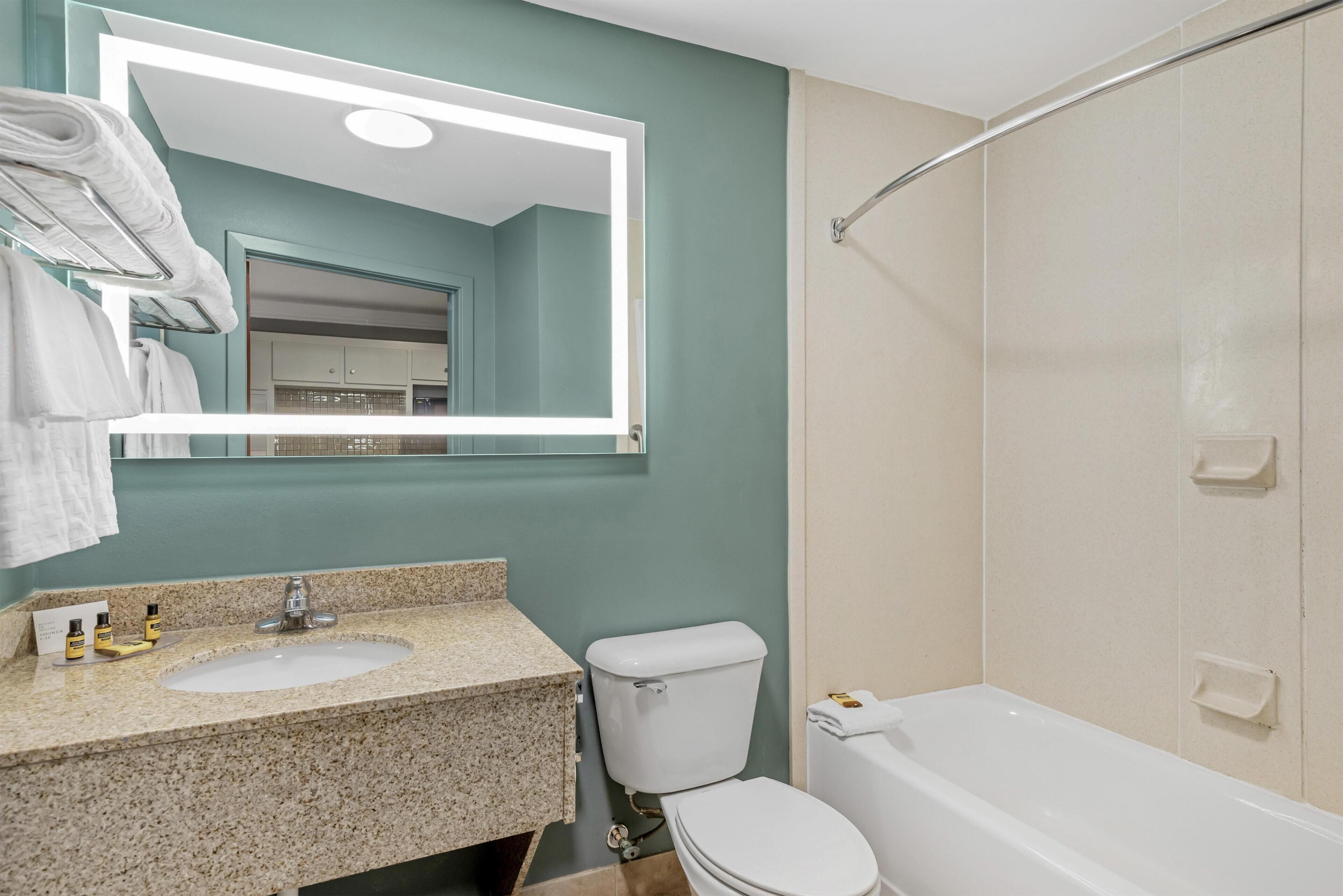 Een badkamer met een wastafel, spiegel, toilet en bad.