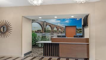 Una reception con una scrivania in legno, un grande specchio e un murale raffigurante un ponte.
