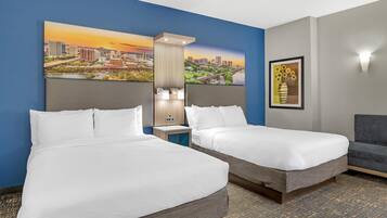 A hotel room with two beds, a nightstand, a lamp, a framed picture on the wall, and a chair.