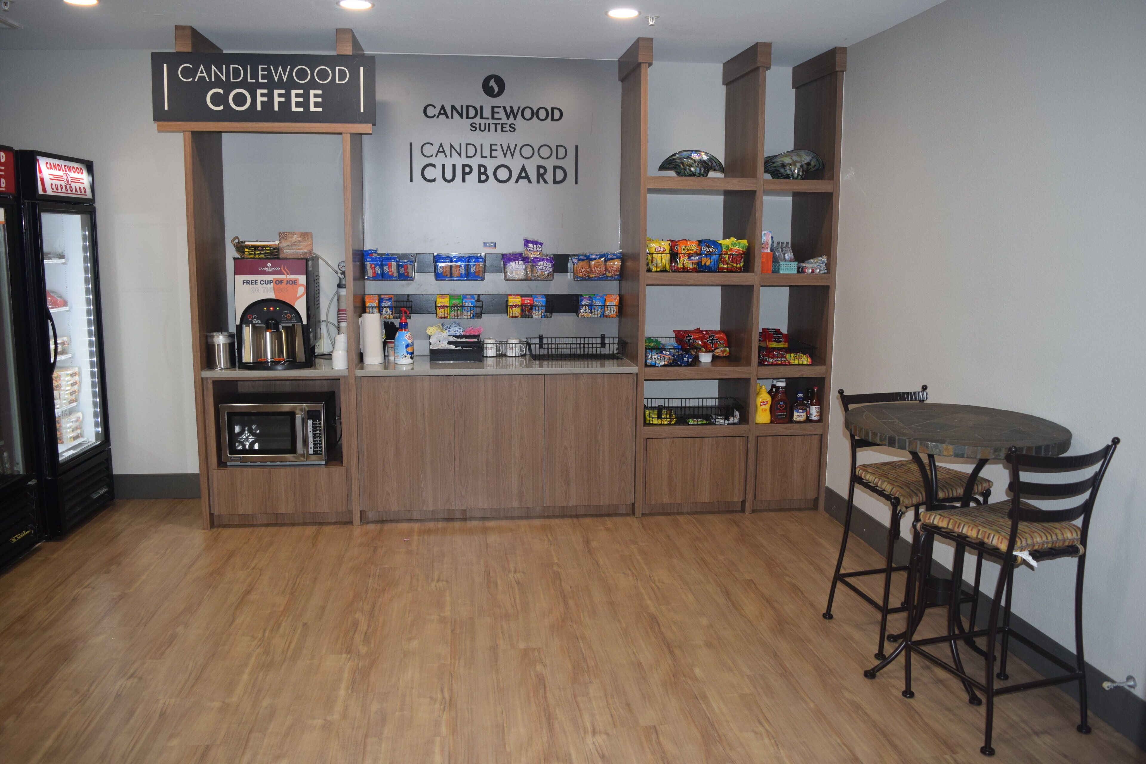 A kitchenette area with a coffee station, microwave, and various food items on shelves.