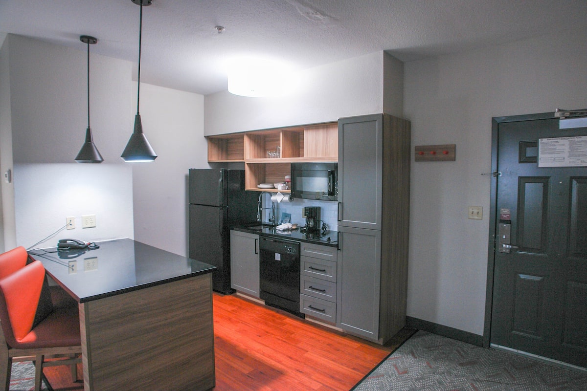 A compact kitchen with a central island, built-in appliances, and a wooden cabinet.