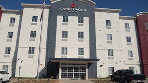 A multi-story hotel with a prominent entrance, a flag, and a parking area.