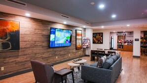 A modern lounge area with a flat-screen TV, comfortable seating, and a coffee station.