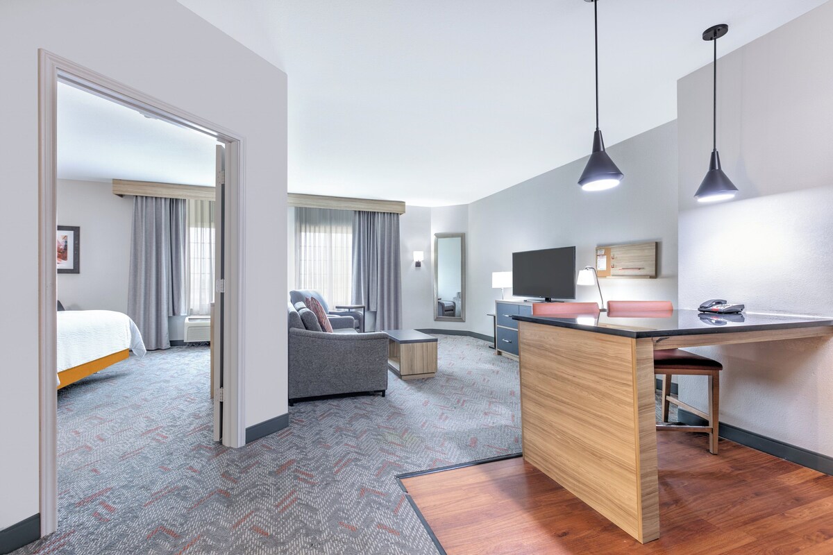 A hotel room with a bed, a sofa, a desk, and a mirror.