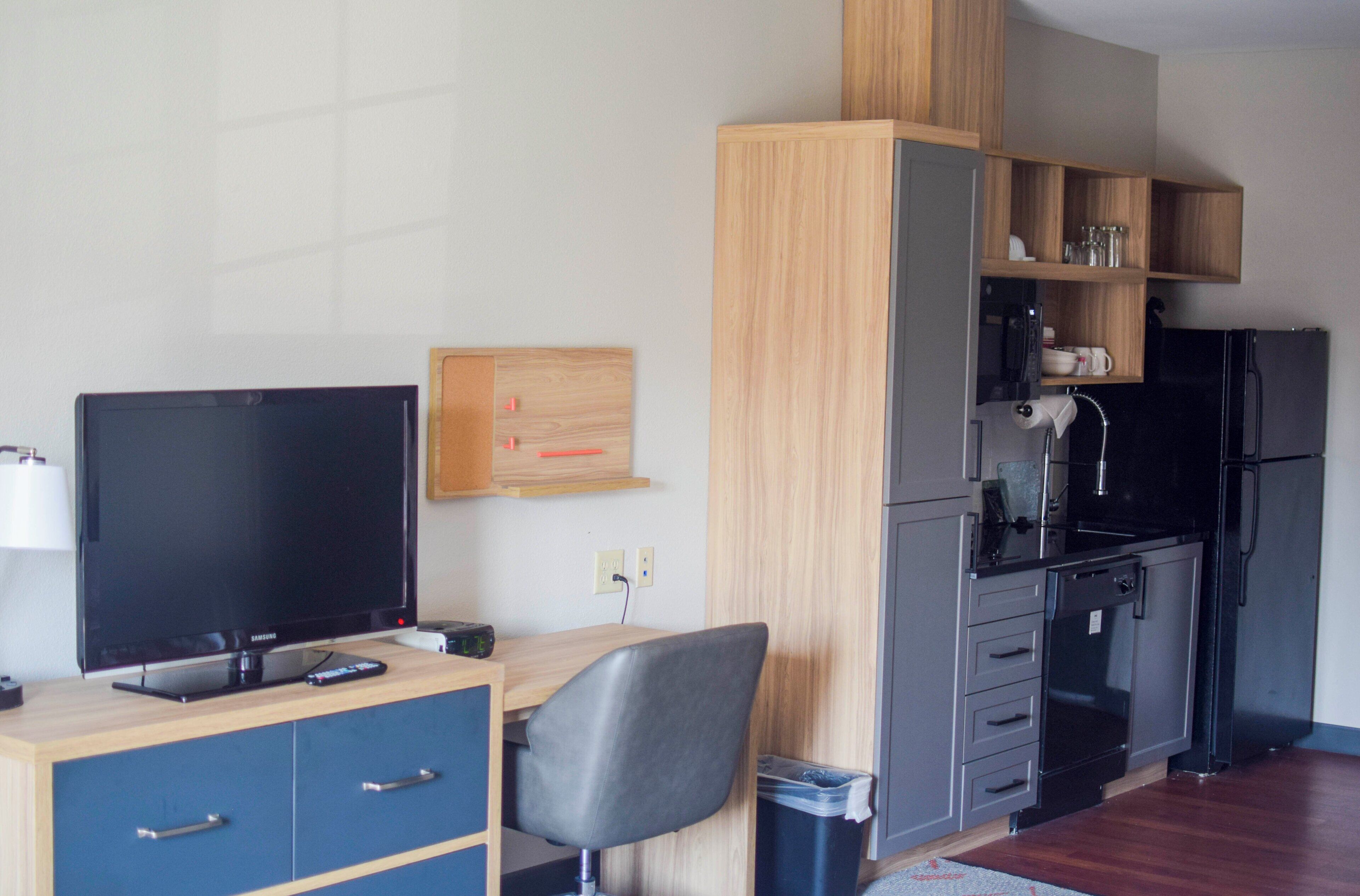 A compact kitchenette with a refrigerator, microwave, and wooden cabinets.