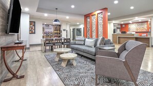 A modern hotel lobby with a seating area, a reception desk, and a kitchenette.