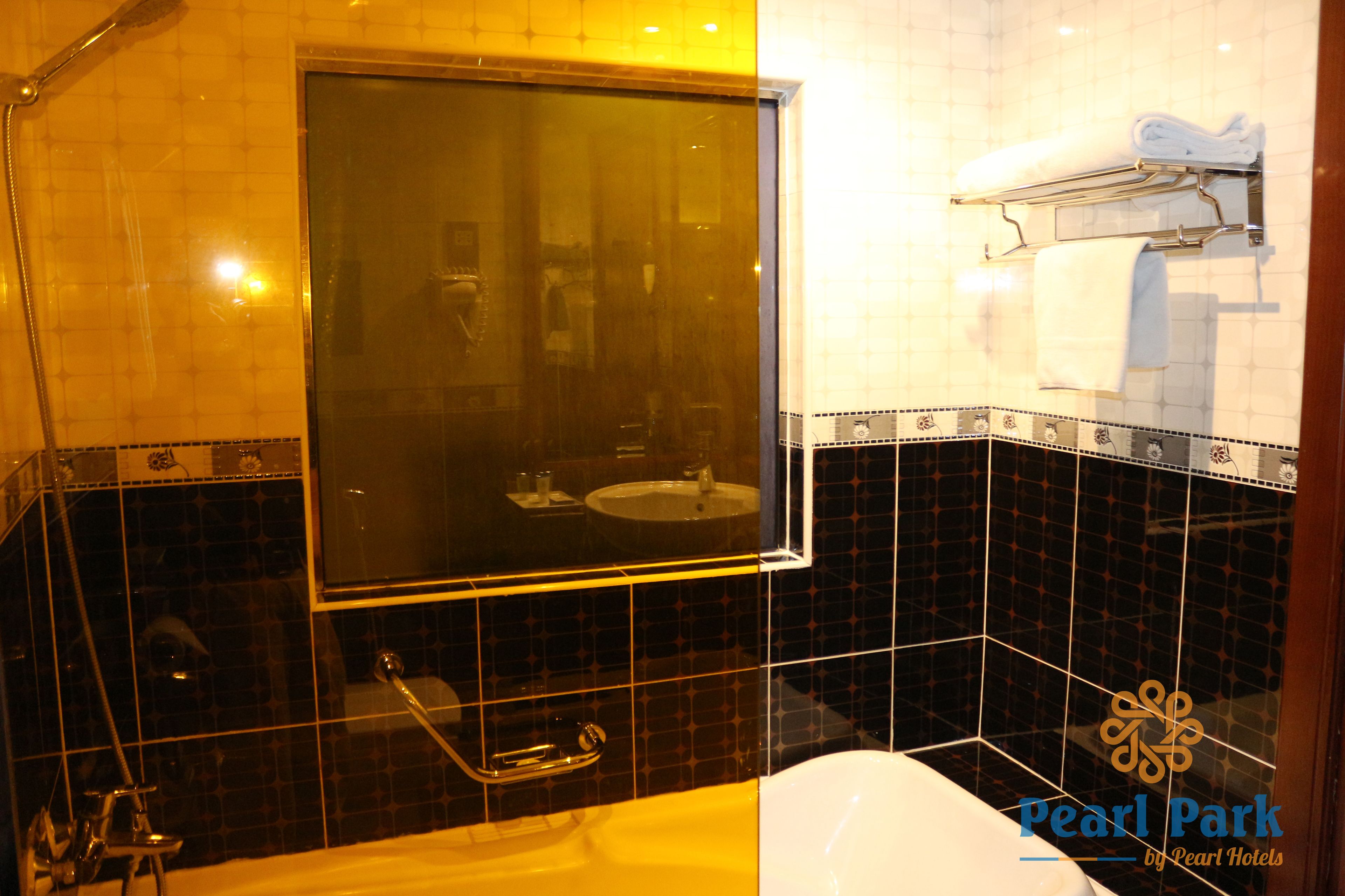 A bathroom with a large mirror, a bathtub, a sink, and a towel rack.
