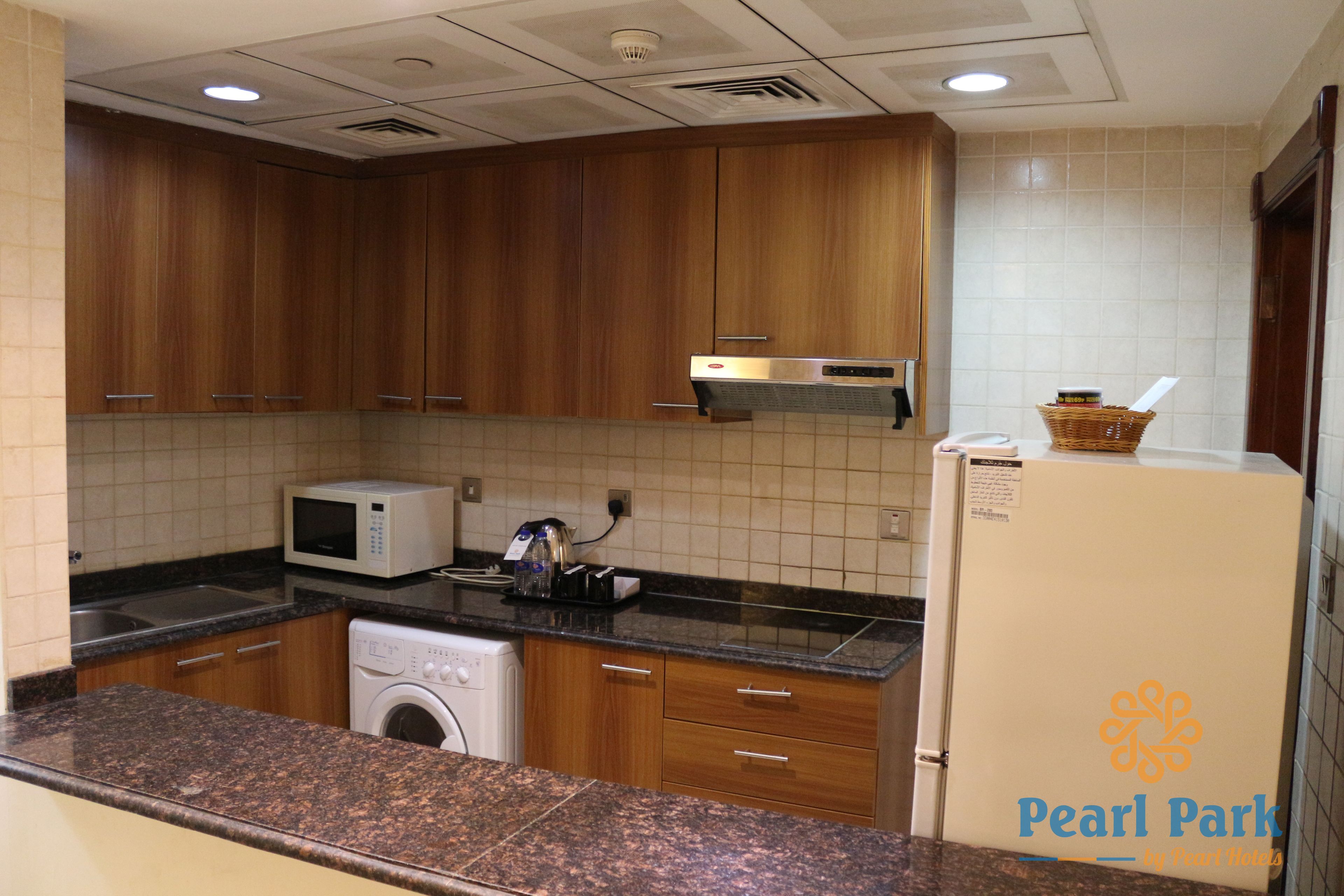 A kitchen with wooden cabinets, a microwave, a washing machine, and a refrigerator.