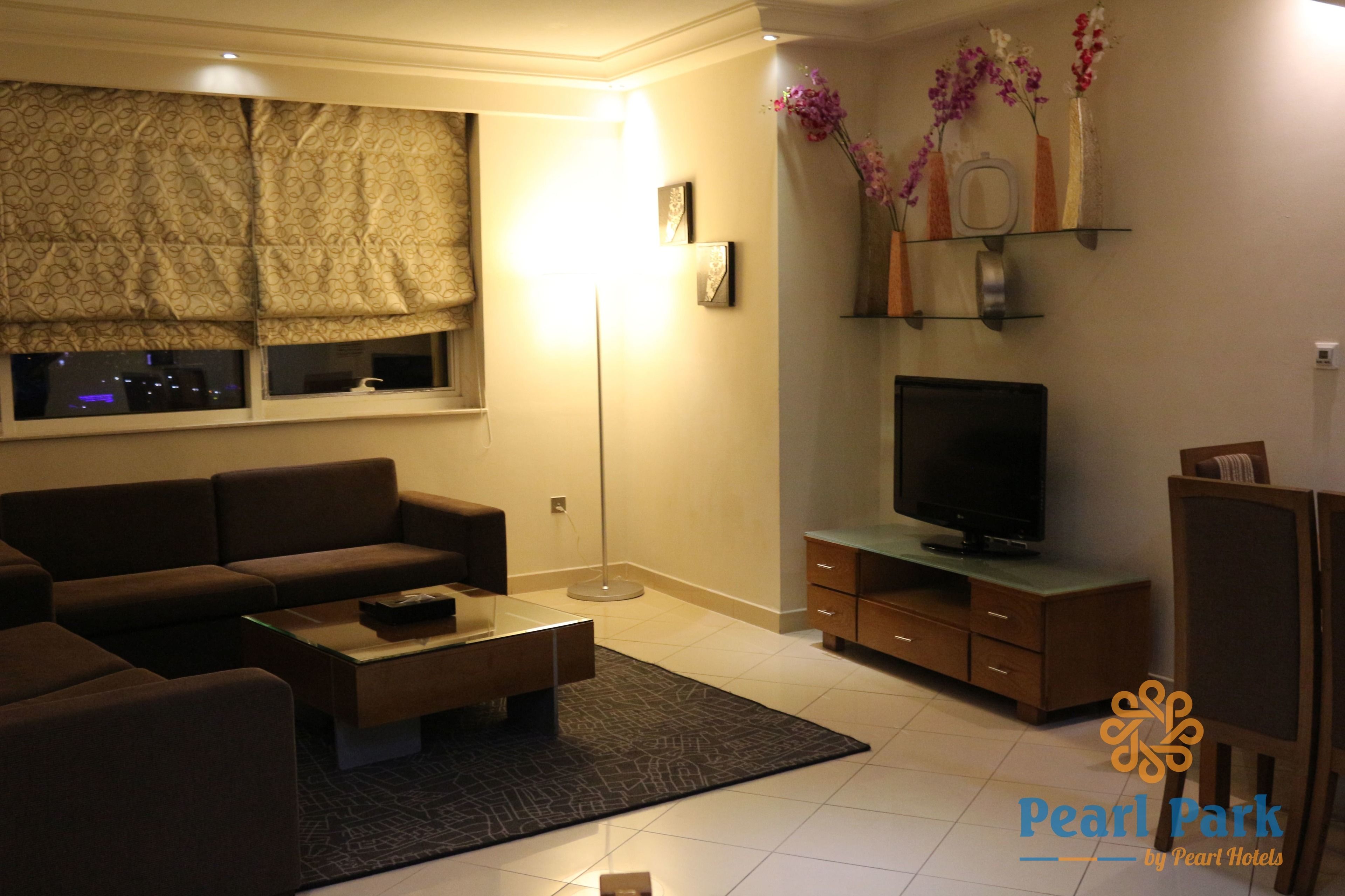 Een moderne woonkamer met een bank, salontafel, televisie en decoratieve accessoires.