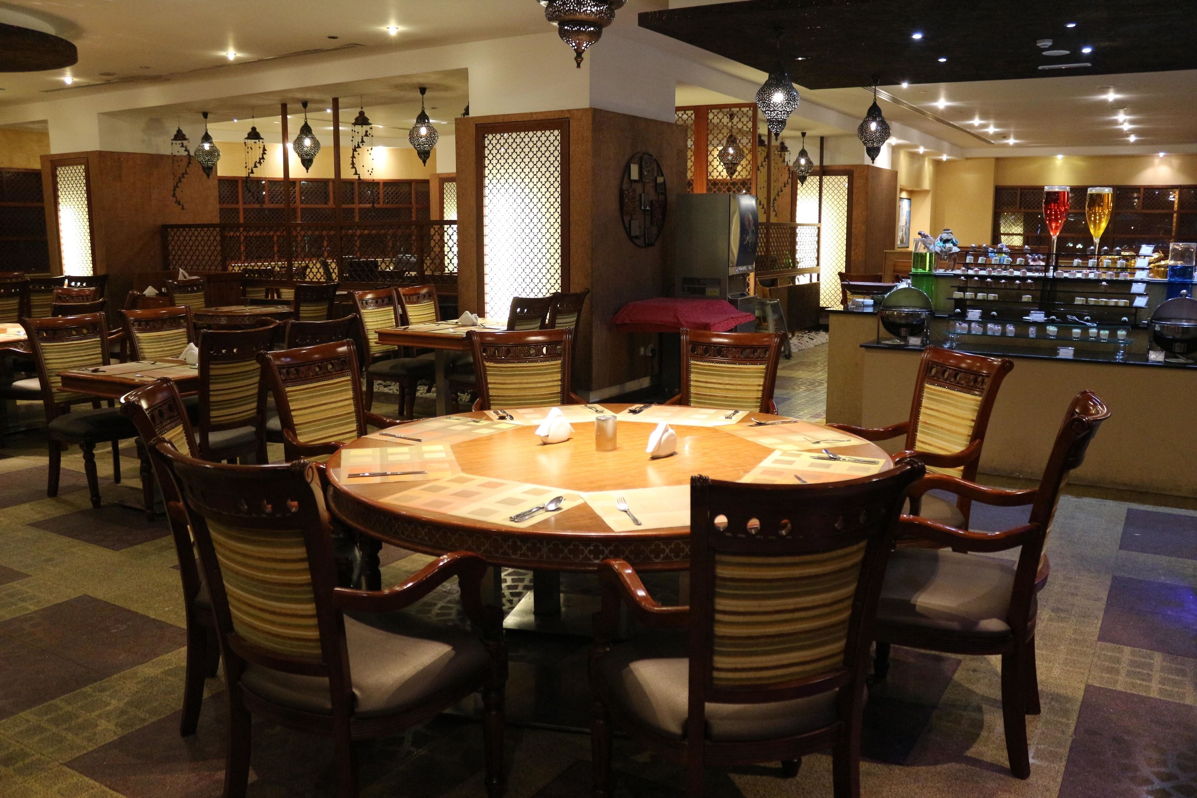 A restaurant with round tables, wooden chairs, and hanging lanterns.