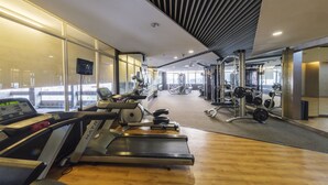 Ein modernes Fitnessstudio mit Laufbändern, Kraftgeräten und einem großen Spiegel.
