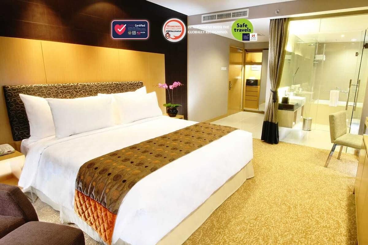 Ein Hotelzimmer mit einem großen Bett, einem Schreibtisch, einem Stuhl und einem Badezimmer mit Duschkabine.