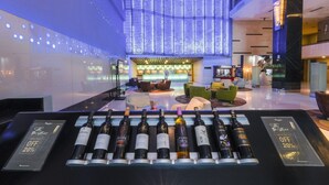 Eine moderne Hotelhalle mit Rezeption, Sitzgelegenheiten und einer Auswahl an Weinflaschen.