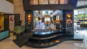 Eine moderne Hotelhalle mit einer Rezeption, einer Treppe zu den oberen Etagen und Blick auf den Speiseraum.