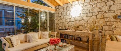 Una sala de estar acogedora con pared de piedra, chimenea, sofá y una mesa de centro.