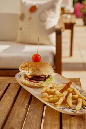 Ein Teller mit einem Burger und Pommes auf einem Holztisch.