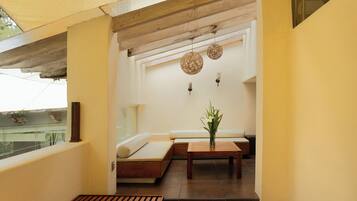 Un interior moderno con un banco de madera, una mesita con un florero y una zona de estar con cojines.