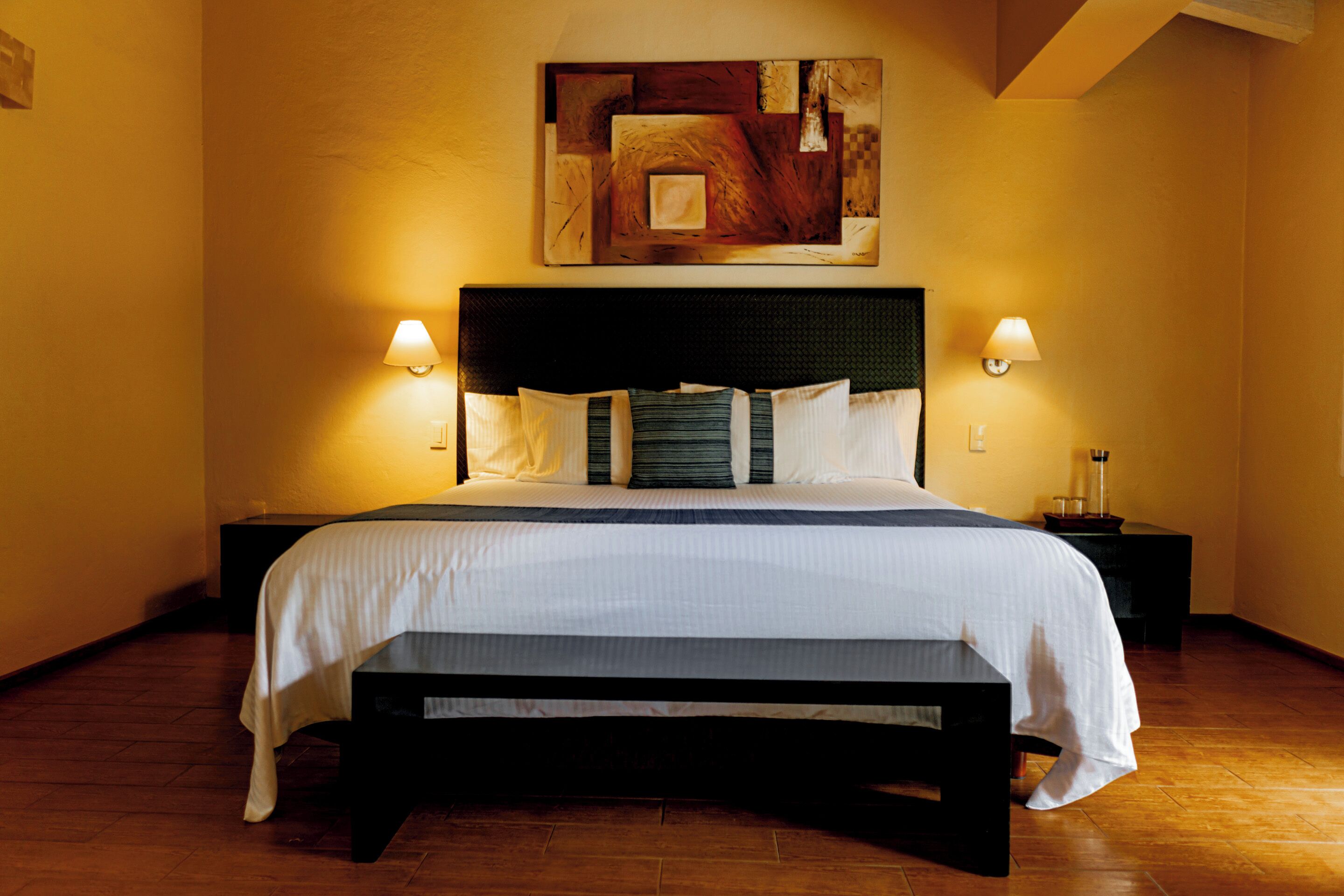 Une chambre d’hôtel avec un grand lit, deux tables de chevet et une œuvre d’art accrochée au mur.