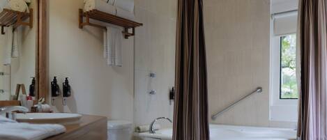 Un baño con inodoro, lavamanos, ducha y ventana con cortinas.