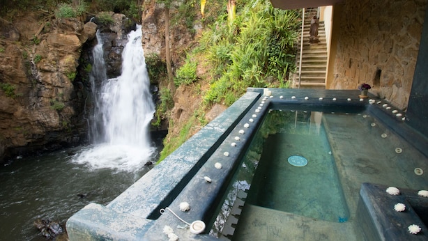 A hot spring area with a waterfall, stone walls, and a stone staircase.
