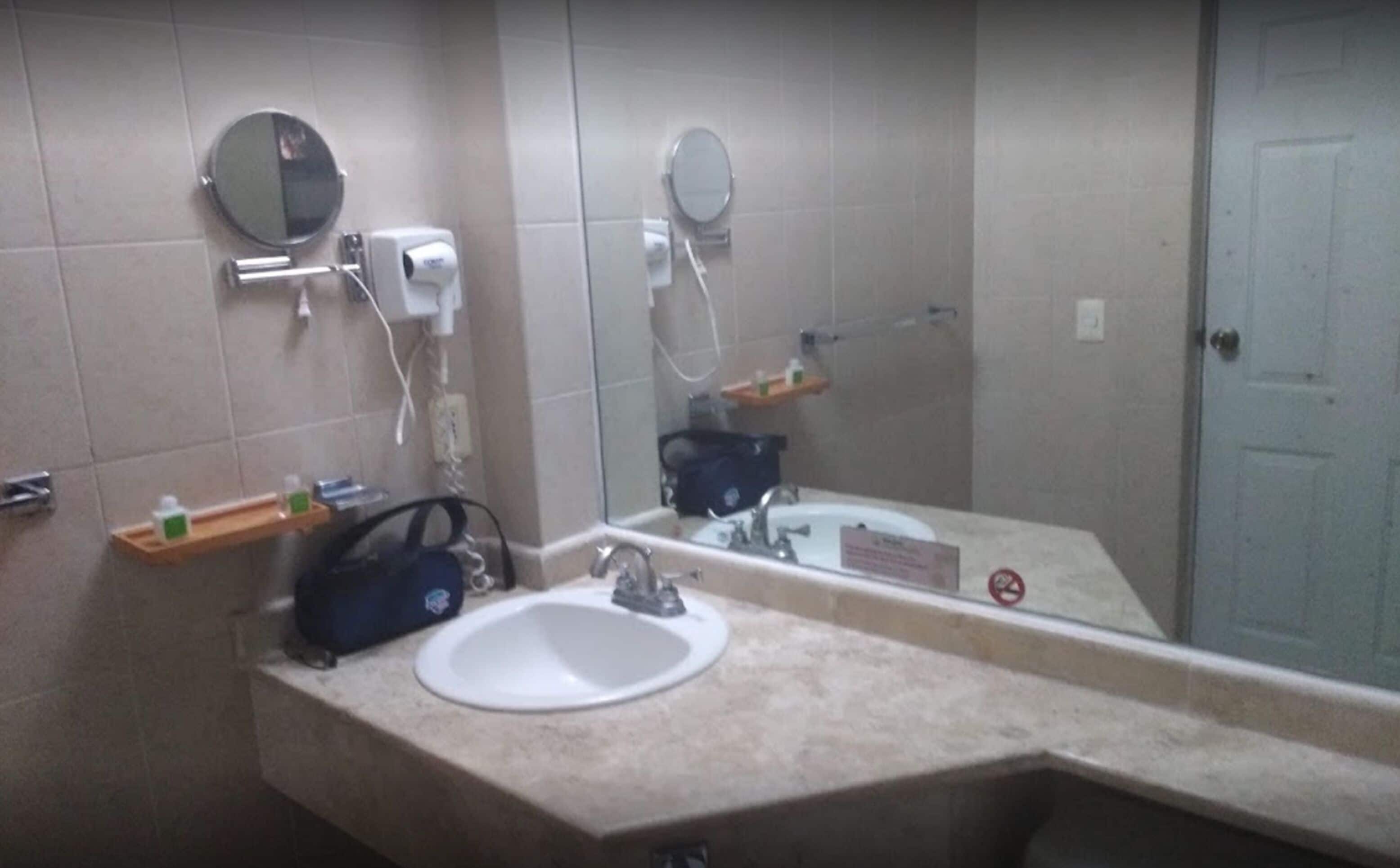 Een badkamer met twee wastafels, een spiegel, een handdoekhouder en een zeepdispenser.