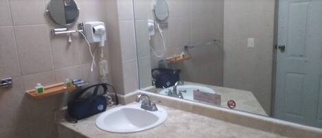 Un baño con dos lavamanos, un espejo, un perchero para toallas y un dispensador de jabón.