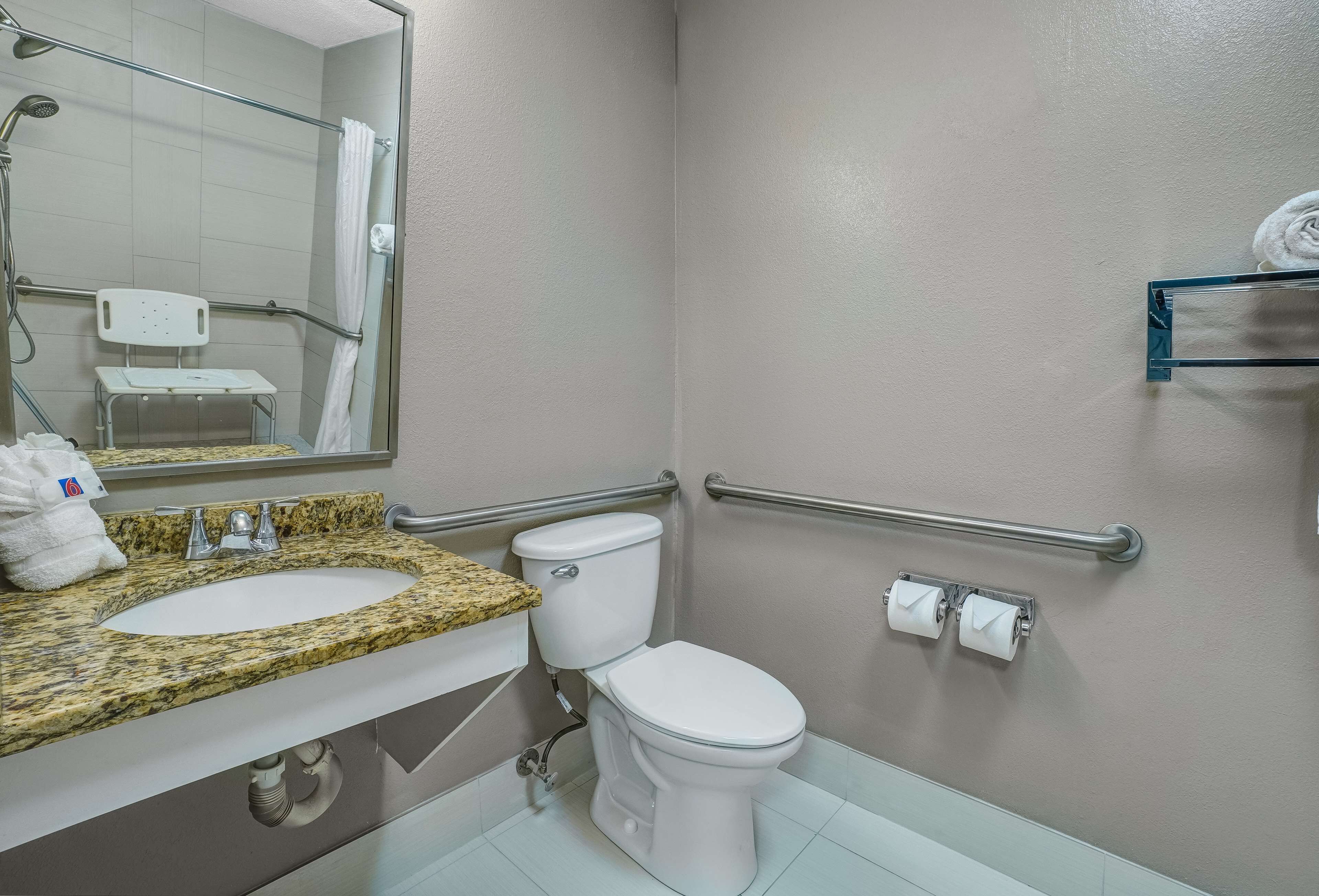 A bathroom with a sink, toilet, and handrails.