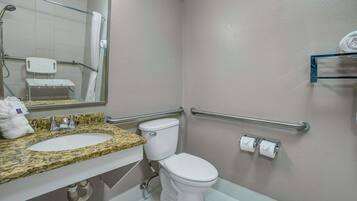 A bathroom with a sink, toilet, and handrails.